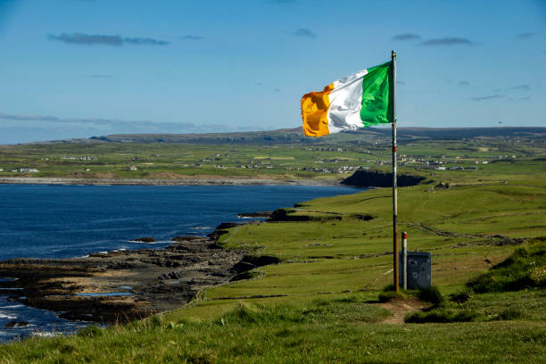 Irish flag at the Cliffs of Moher, Clare, Ireland Irish flag at the hiking trail leading from Doolin to the Cliffs of Moher, County Clare, Ireland doolin photos stock pictures, royalty-free photos & images