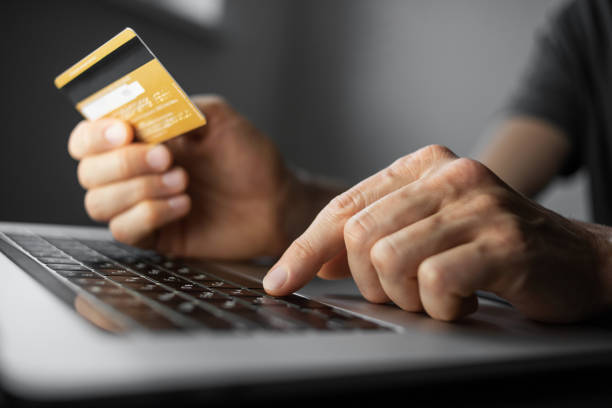 istock Paying online. Young man using laptop with credit card at home 1311955285