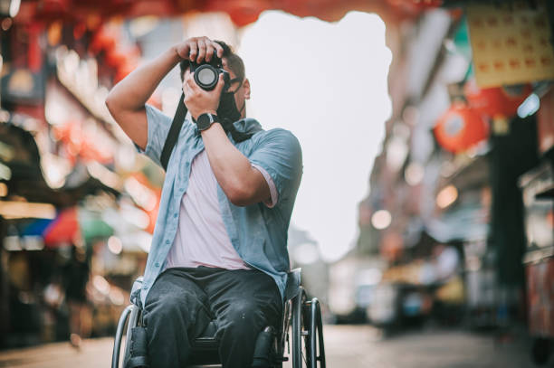asian chinese male with physical disability on wheelchair photographing in china town sitting on his wheelchair asian chinese male with physical disability on wheelchair photographing in china town sitting on his wheelchair chinatown photos stock pictures, royalty-free photos & images