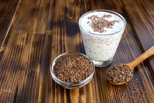 yogurt o kefir con semi di lino nel bicchiere da bere sullo sfondo di legno marrone - seme di lino foto e immagini stock