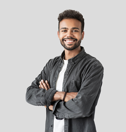 Cheerful young man with folded arms studio shot. Isolated on gray background