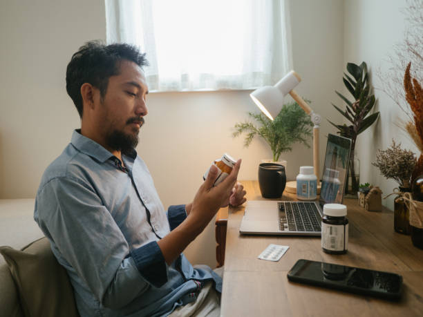 asiatische mann ein video telemedizin anruf mit einem arzt. - pill capsule prescription pill bottle stock-fotos und bilder