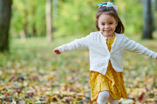 Happy running pretty girl on blurred autumn park background