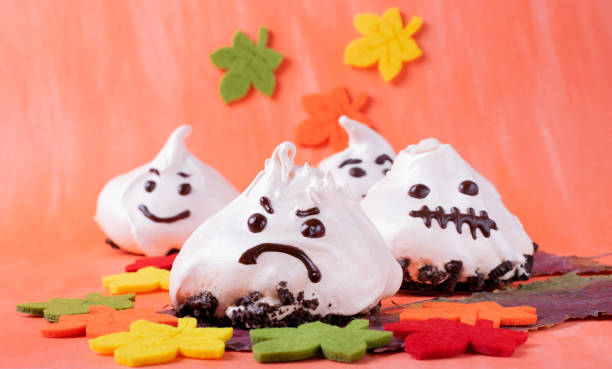 istock Funny meringue ghosts with funny faces on orange 1311965947