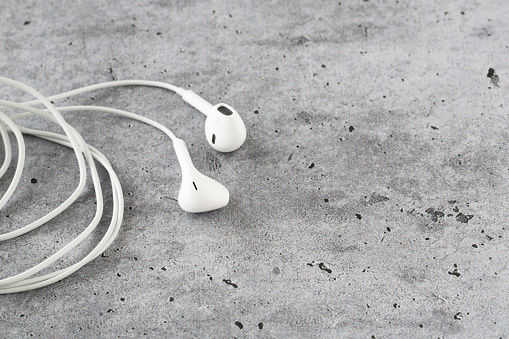 close-up of white earphones on gray background with copy space