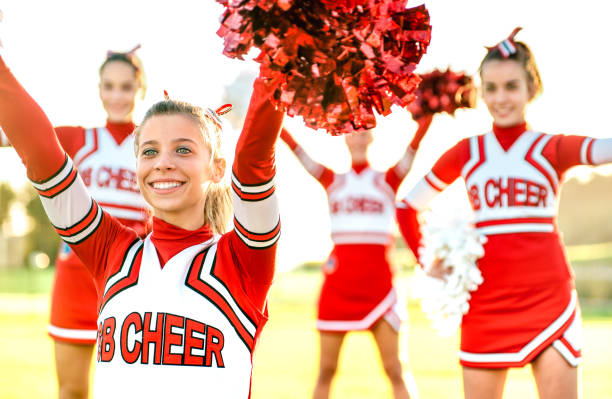 gruppe von cheerleaderinnen, die im freien auf dem universitätscampus auftreten - sportkonzept des cheerleader-teamtrainings an der high school bei sonnenuntergang - warmer hintergrundbeleuchtungsfilter mit fokus auf linke mädchenaugen - child american football football sport stock-fotos und bilder