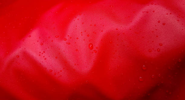 grosses gouttes d’eau sur un textile rouge avec un effet imperméable à l’eau. imprégnation hydrofuge. gouttes de texture sur le tissu - clothing store photos et images de collection