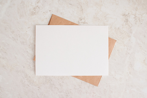 Layout of sheet of paper on craft envelope and marble texture. Horizontal canvas template for greeting, wedding cards, invitations. Natural beige colors.