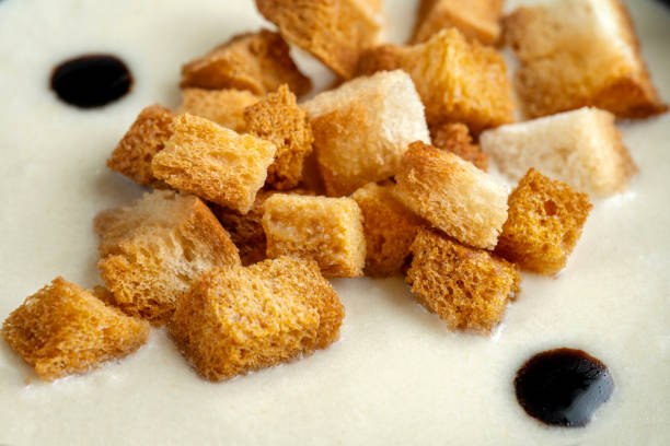 Wheat bread croutons in a white puree soup. Macro.
