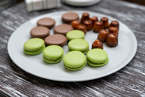 Cookies of pasta, green and brown colors, as well as other sweets, are laid out on a plate. Festive event.