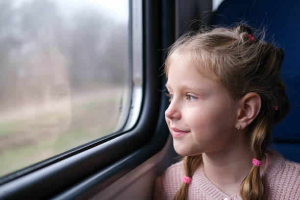 The child is on the train and looks out the window. A little girl travels in a train. The child is on the train and looks out the window. A little girl travels in a train. electric train photos stock pictures, royalty-free photos & images