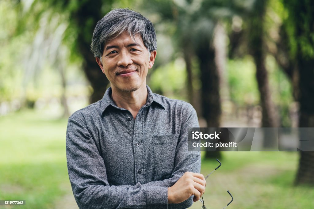 Mid age Chinese ethnicity man in the park Portrait of a middle aged Chinese ethnicity man in a park Men Stock Photo