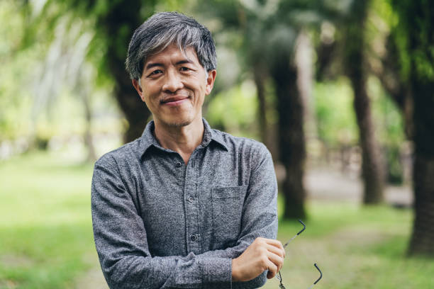 Mid age Chinese ethnicity man in the park Portrait of a middle aged Chinese ethnicity man in a park asian and indian ethnicities stock pictures, royalty-free photos & images