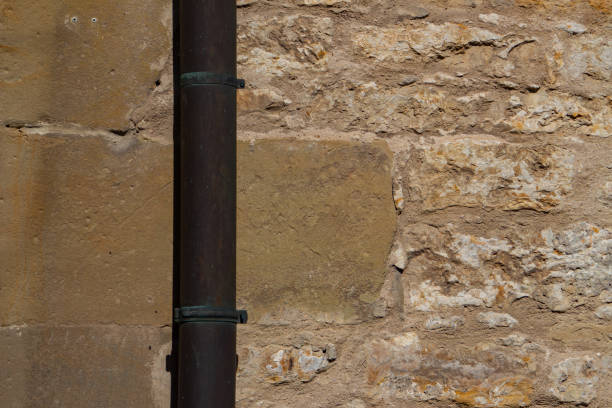 istock Downpipe in front of a sandstone and natural stone wall with copy space 1311977958