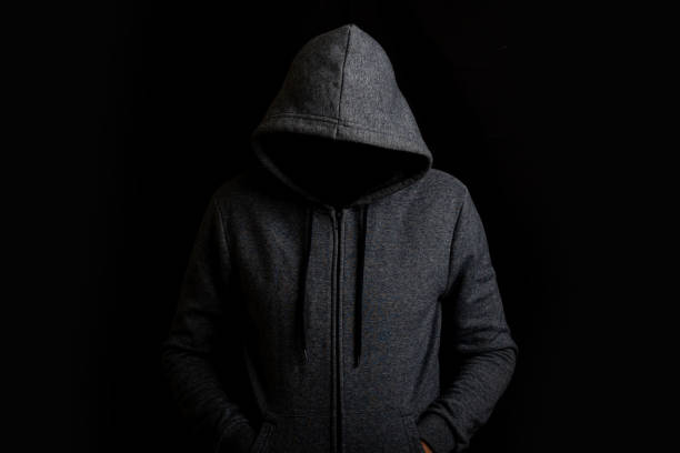 istock Man without a face in a hood on a dark background 1311983247