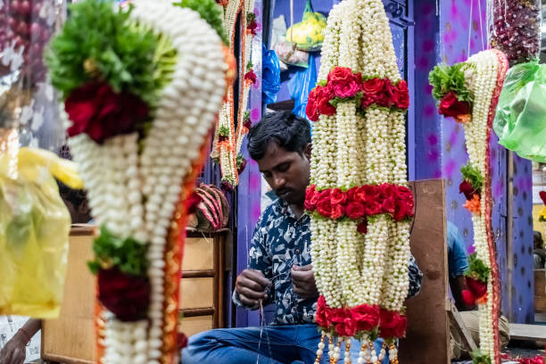 a flower seller working in his colorful shop - india bangalore flower business imagens e fotografias de stock