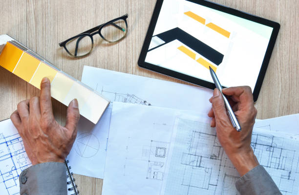 a top view of architect working desk with hand writing and draw on equipment for drawings pens sketched idea on wood table, the concept of modern technology for architectural working with tablet una vista superior del escritorio de trabajo del arquitecto con escritura a mano y dibujar en el equipo para los dibujos plumas esbozaron la idea en la mesa de madera, el concepto de tecnología moderna para el trabajo arquitectónico con tableta