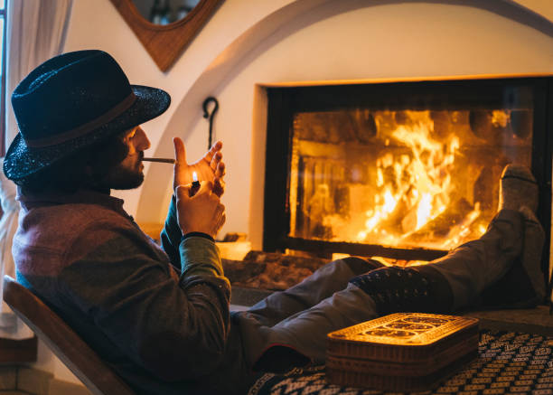 istock Young man relaxes by fire and smokes cbd joint 1311985808