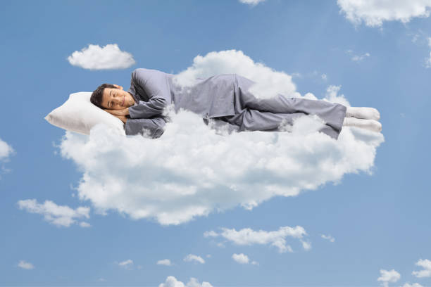 istock Man in pajamas sleeping on a cloud and floating in the sky 1311985836