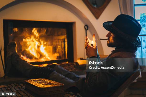 Young Man Relaxes By Fire And Smokes Cbd Joint Stock Photo - Download Image Now - Cannabis Plant, Smoking - Activity, Marijuana - Herbal Cannabis