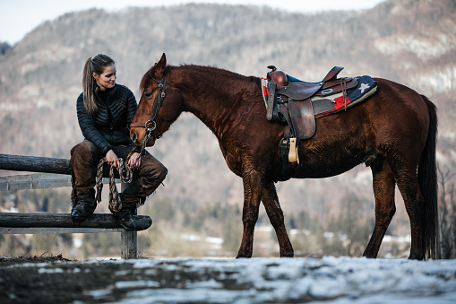 Young woman hugging her horse in nature before a ride