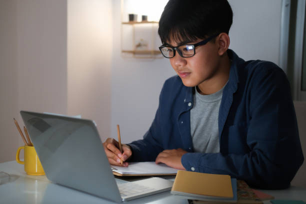 istock Young collage man learning online at night at his home. 1311988158