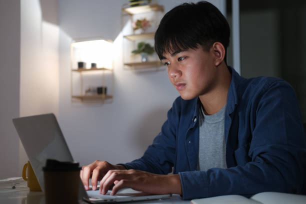 istock Young collage man learning online at night at his home. 1311988163
