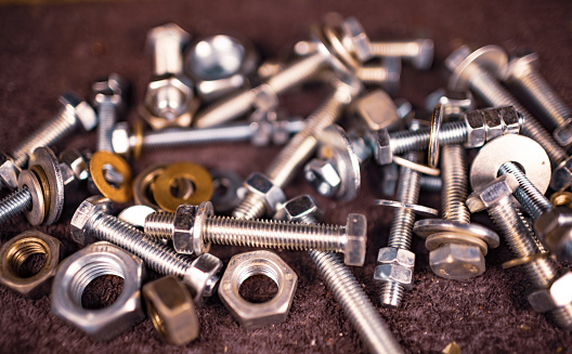 Metal nuts bolts and a wrench lie on the work table of the assembler in a chaotic order. Background concept for fasteners and construction topics. Repair and spare parts concept