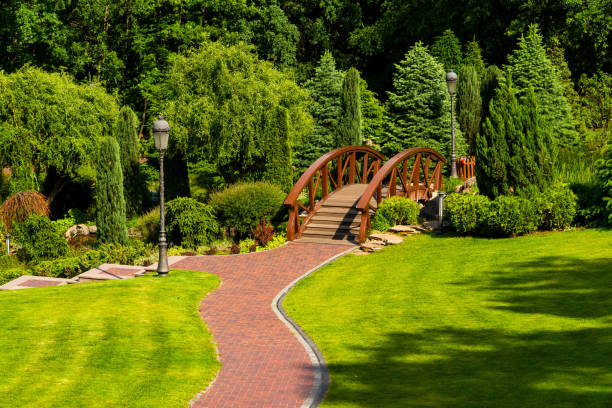 A path of red bricks leading to a wooden bridge in a landscape park in summer