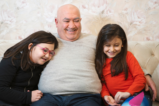 Granddaughters embracing her grandfather at home