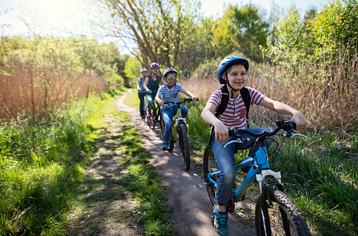 Mother and kids are enjoying a bike trip together  on a sunny spring day\nNikon D850