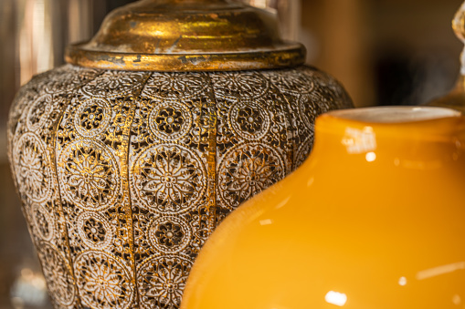 Handmade perforated copper vase in front alongside a modern glass vase