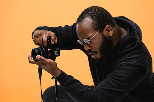 Portrait of beard African American professional cameraman with glasses in the studio.