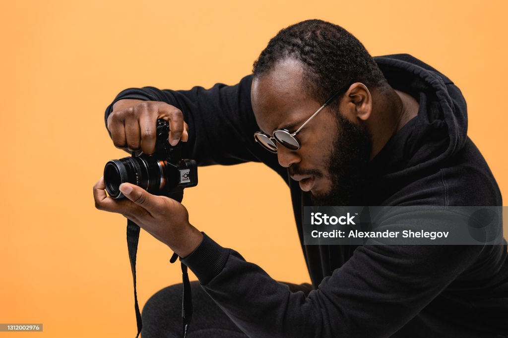 Portrait of beard African American professional cameraman with glasses in the studio. Photographer Stock Photo