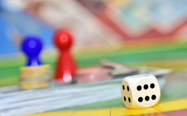 istock Dice and red and blue figures in background on the board game. 1312004739