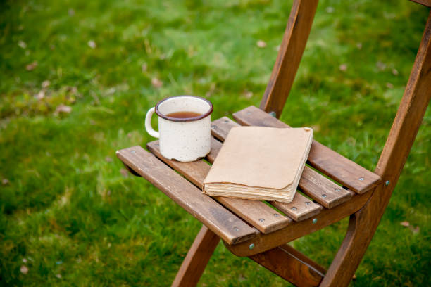 istock Old book with cup of tea on a table on green grass in spring 1312006988