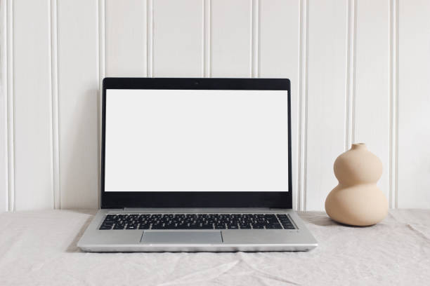 istock Modern minimal workspace composition. Notebook mock-up scene. Organic shaped ceramic vase and laptop on beige linen tablecloth background. White wooden wall. Scandi design. Home office concept. 1312009936