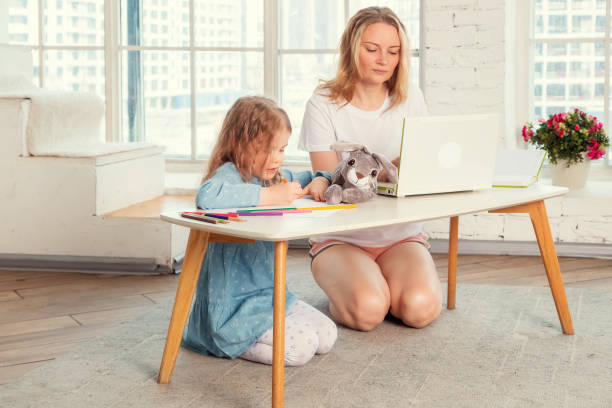 istock mom is working on a laptop and her daughter is drawing 1312009986