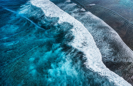 Coast with high waves as a background from top view. Blue water background from top view. Summer seascape from air. Indonesia. Travel and vacation image.
