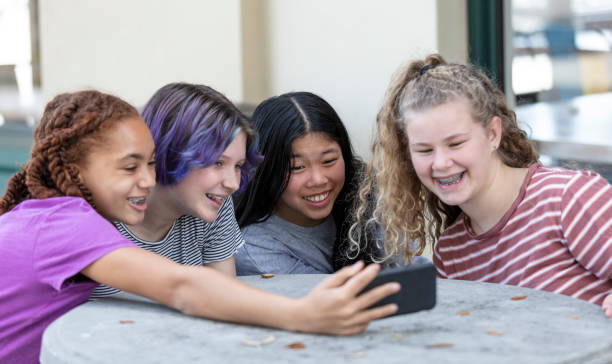 istock Four tween girls watching video on mobile phone 1312018653