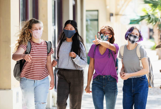 istock Four tween girls walking on sidewalk, wearing masks 1312018682