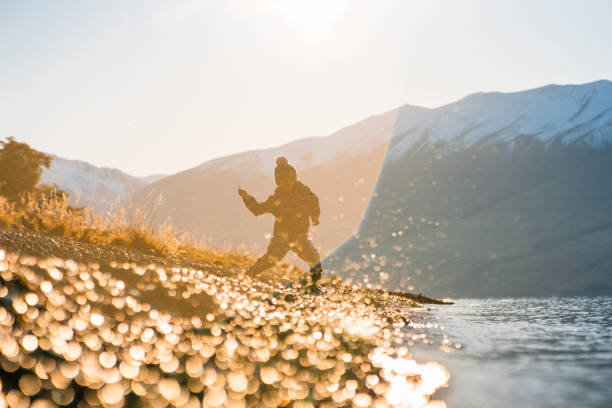 Kid throwing pebbles in lake Ohau, Canterbury, South Island, New Zealand.