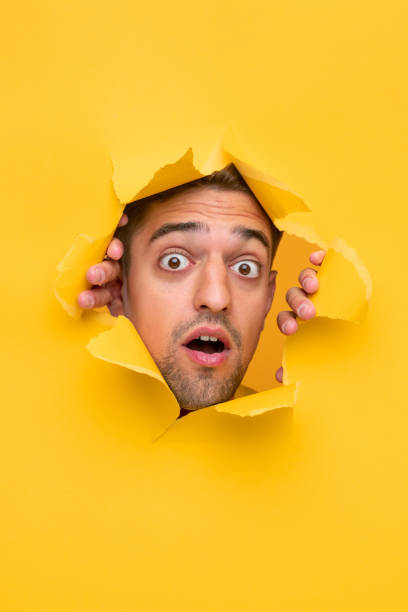 istock Shocked guy peeking from hole in paper 1312022115