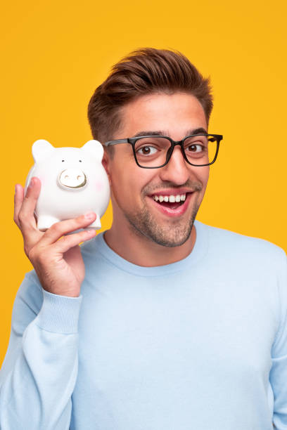 istock Smiling man demonstrating white piggy bank 1312022143