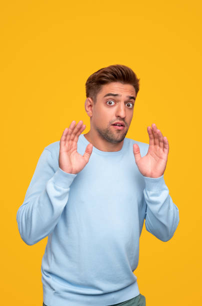 istock Confused young man with hands raised looking at camera with surprise in studio 1312022154