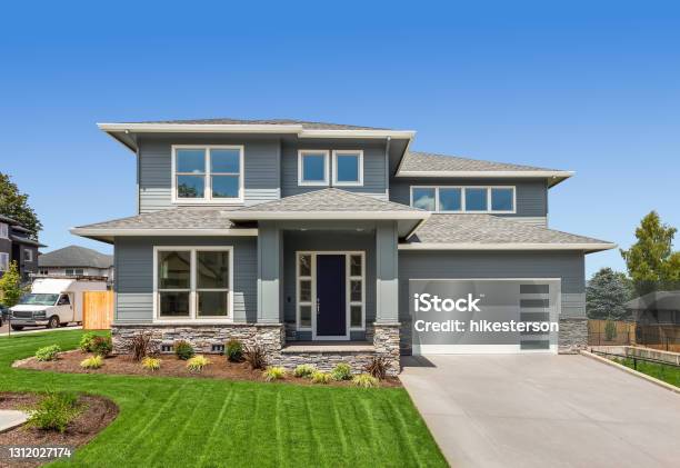 Beautiful Suburban Home Exterior On Bright Sunny Day With Green Grass And Blue Sky Stock Photo - Download Image Now