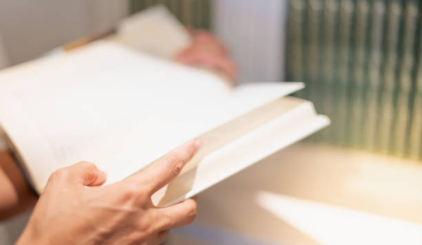 istock Female hand holding notebook and reading book for relax and the knowledge while sitting on the sofa in the living room in their house. 1312028696