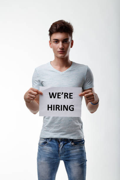 joven casual en jeans sosteniendo un cartel de we're hiring a su - mer people fotografías e imágenes de stock