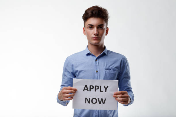 istock Attractive young man holding a sign with text - Apply Now 1312041628