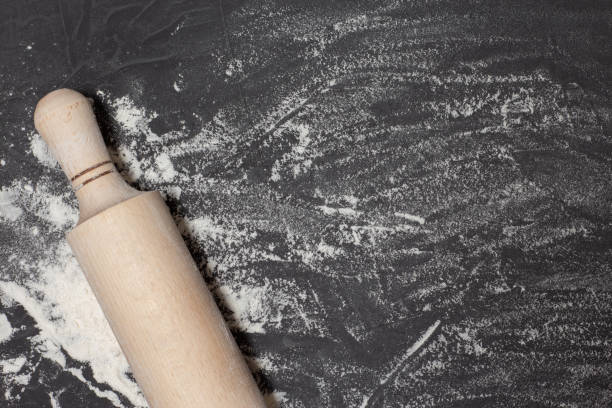 istock Rolling pin and white flour on black stone table. Banner for web with free space for your text. Concept for bakery shop. Top view, copy space 1312044459